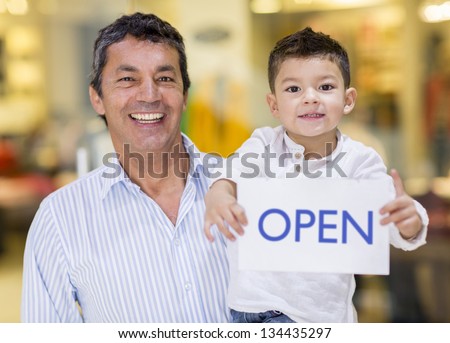 Business owner and son holding an open sign