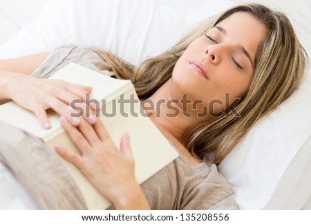 Beautiful woman falling asleep while reading a book