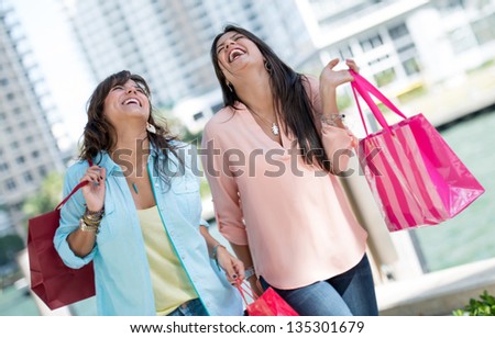 Happy shopping girls laughing and carrying bags