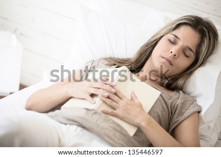 Woman falling asleep while reading a book in bed
