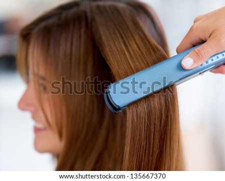 Woman at the beauty salon straightening hair