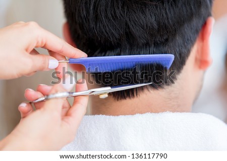 Stylist cutting hair of a man with scissors