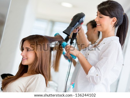 Stylist Drying Hair Of A Female Client At The Beauty Salon
