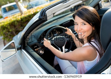Female driver looking very happy driving a car
