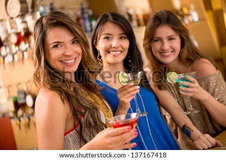 Beautiful group of girls having drinks at the bar and smiling