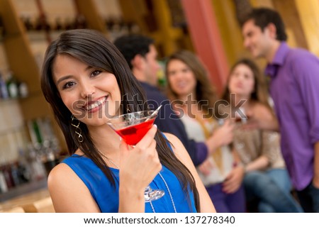 Woman at the bar having a drink and looking happy