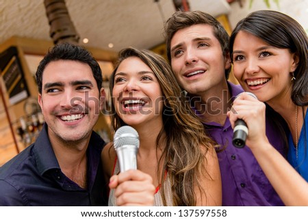 Group of people karaoke singing at the bar having fun