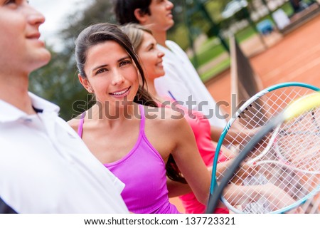 Female tennis player with a group at the court and smiling