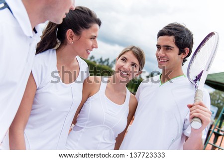 Group of happy tennis players talking at the court