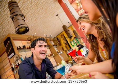 Women paying barman for drinks at the bar with cash and