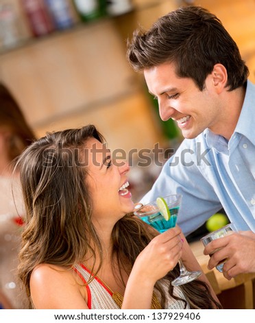 Romantic couple having drinks at a club and smiling