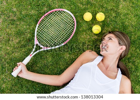 Tennis player lying on the floor with racket and ball