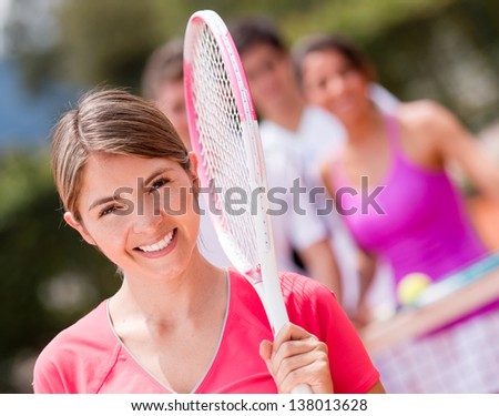 Happy woman at the tennis court smiling with a racket