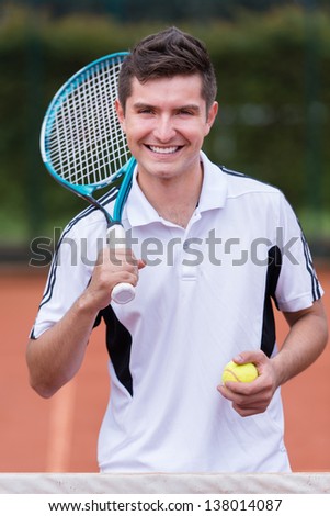 Happy male tennis player smiling at the court