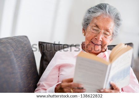 Elder woman reading a book at home and smiling