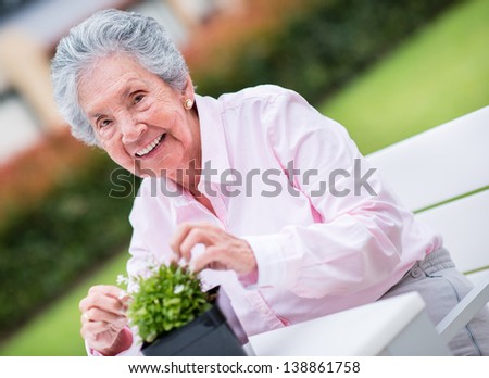 Retired woman fixing a plant outdoors enjoying gardening