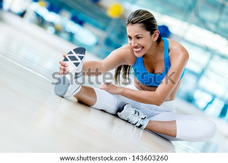 Beautiful woman stretching at the gym looking happy Beautiful woman stretching at the gym looking happy