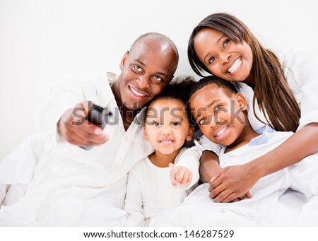 Happy family watching tv in bed - isolated over white