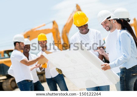 Group of architects at a construction site looking at blueprints