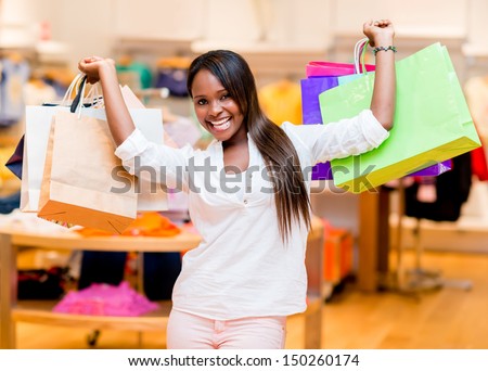 Excited shopping woman holding bags with arms up