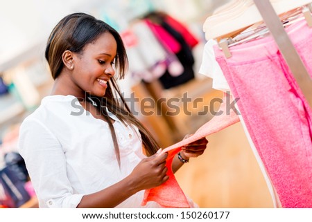 Happy female shopper looking al clothes at a retail store