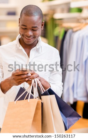 Shopping man texting on his phone at a store