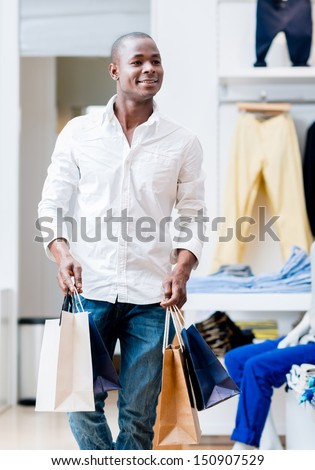 Happy shopping man at a retail store carrying bags