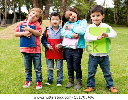 Happy group of school kids holding notebooks outdoors