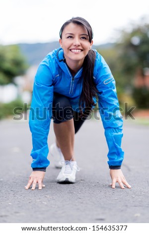 Fit woman set in a position to start running outdoors