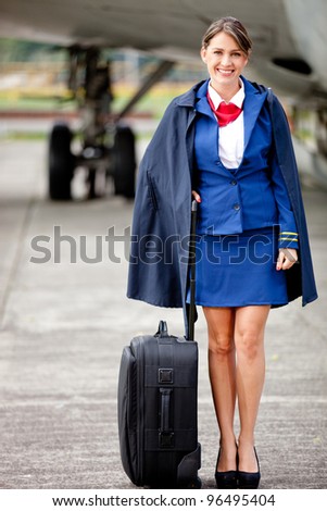 Beautiful flight attendant with her bag next to a aiplane