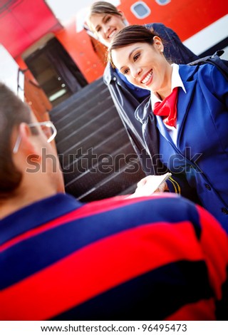 Friendly air hostesses welcoming passenger into the airplane