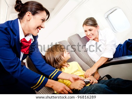 Air hostess helping a kid to fasten his seatbelt