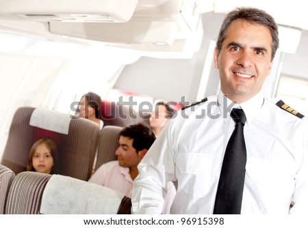 Friendly pilot in the passengers cabin of an airplane smiling