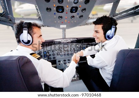 Pilots in an airplane cabin handshaking after a successful flight