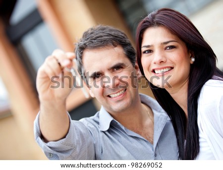 Beautiful couple holding keys and smiling - outdoors