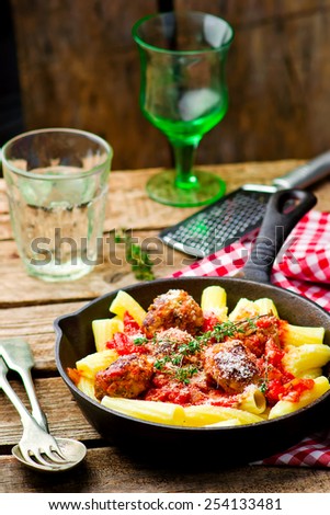 meat balls in tomato sauce with pasta in frying pan. style rustic. selective focus.