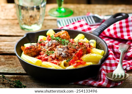 meat balls in tomato sauce with pasta in frying pan. style rustic. selective focus.
