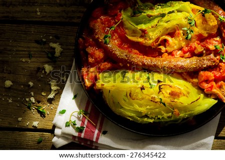 The baked cabbage with sausages and sauce in a vintage frying pan on wooden a table. Style rustic. selective focus