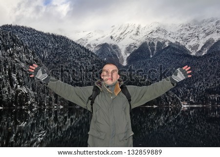 A man stands, arms outstretched, amidst the mountain panoramas A man stands, arms outstretched, amidst the mountain panoramas