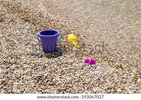 Colorful children\'s toys scattered on the sand at the beach in sunny day