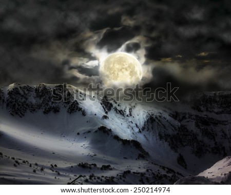 The full moon in the sky over the mountain snow peak in Krasnaya Polyana Sochi