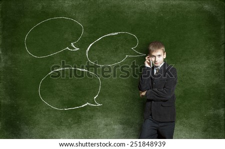 Boy with mobile phone against the background of the drawing with chalk on the Blackboard