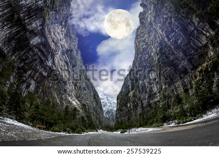 The road was built in the mountains, leading to Lake Ritsa in light of the full moon, Abkhazia, Caucasus