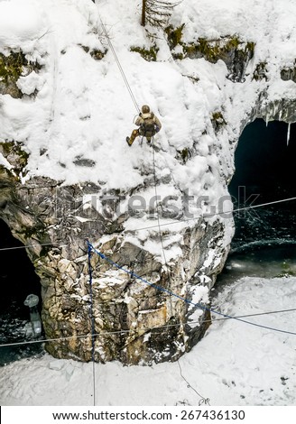 Male in mountain climbing gear is coming down to a cave in the Mountain Park of Ruskeala in Karelia, Russia , 01 March 2015