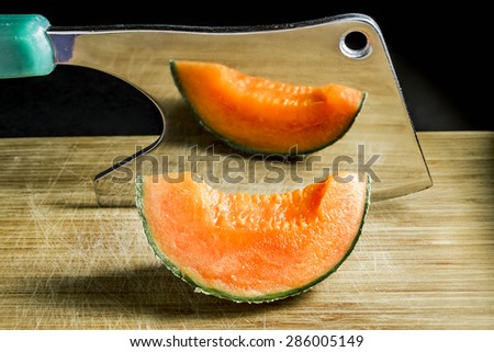 piece of succulent Orange melon rests on the Board with an axe