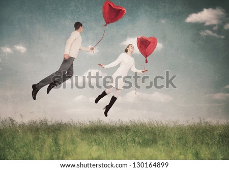 The young woman and the man flying by a balloon in the form of heart