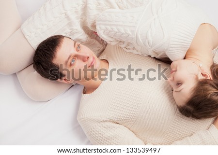 girl and the young man in white knitted jackets lie on a sofa