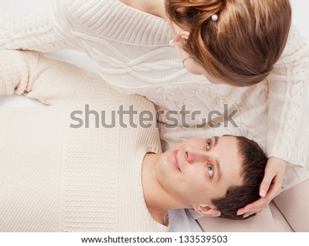 girl and the young man in white knitted jackets lie on a sofa