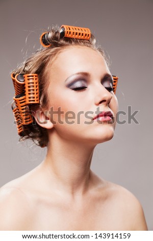 Stylish girl portrait with fashion makeup and hair curlers, isolated on grey background, hair and beauty treatment concept
