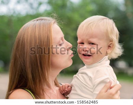 Portrait of a Crying Little Boy who is Being Held by her Mother, Outdoors